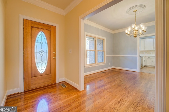 foyer with an inviting chandelier, crown molding, and light hardwood / wood-style floors