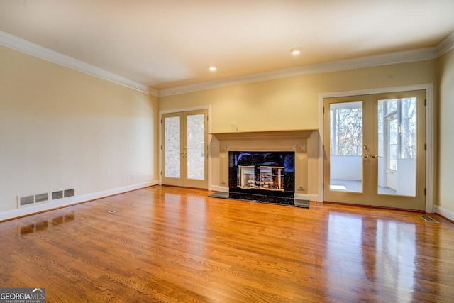 unfurnished living room featuring ornamental molding, hardwood / wood-style floors, a high end fireplace, and french doors