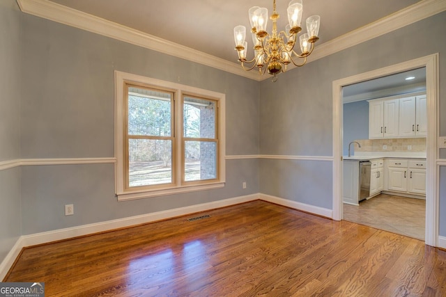 unfurnished dining area featuring crown molding, a chandelier, sink, and light hardwood / wood-style flooring