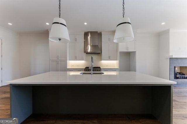 kitchen with a large island, decorative light fixtures, and wall chimney range hood