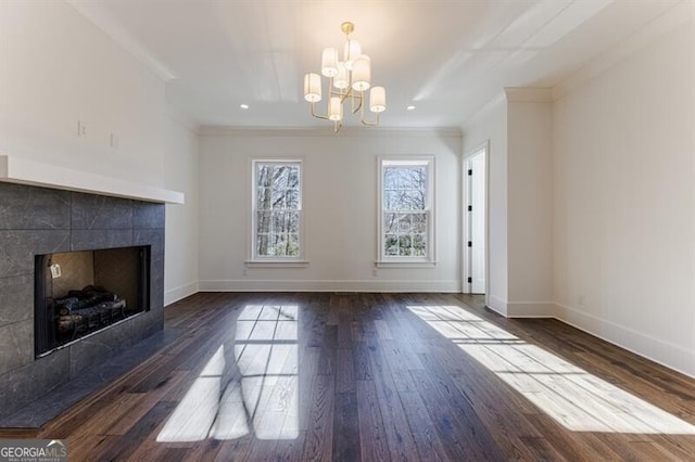 unfurnished living room with dark hardwood / wood-style flooring, a notable chandelier, ornamental molding, and a tile fireplace