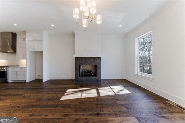 unfurnished living room featuring crown molding, a fireplace, dark hardwood / wood-style floors, and a notable chandelier