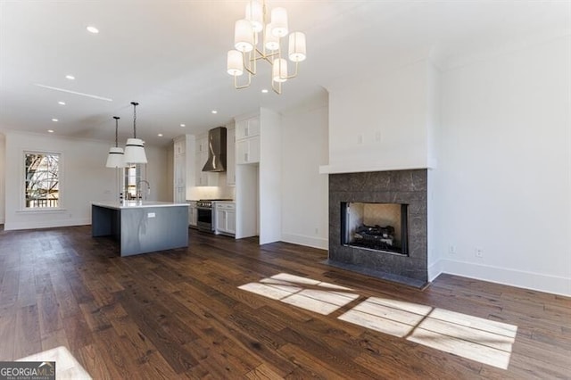 unfurnished living room with an inviting chandelier, dark hardwood / wood-style flooring, a tiled fireplace, and sink