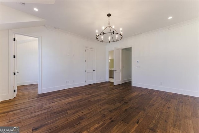 spare room with crown molding, dark hardwood / wood-style floors, and a chandelier