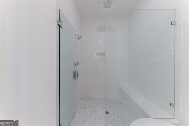 bathroom featuring toilet and a shower with shower door