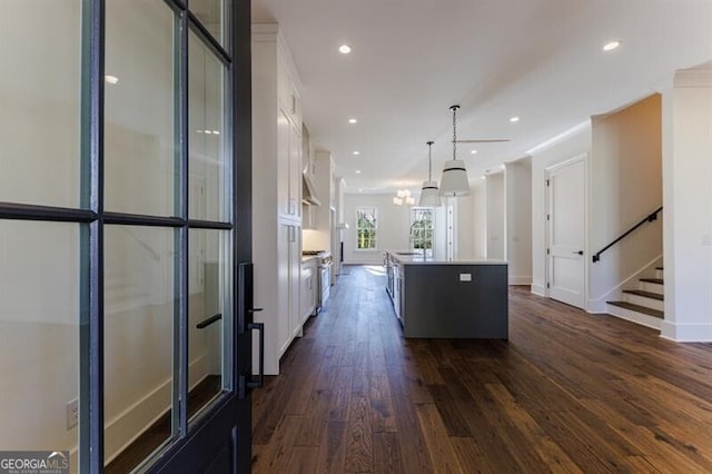 kitchen featuring pendant lighting, dark hardwood / wood-style flooring, an island with sink, and white cabinets