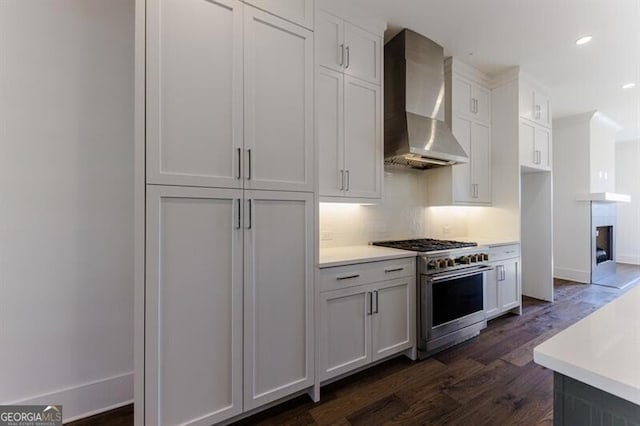 kitchen with white cabinets, stainless steel range, dark hardwood / wood-style floors, and wall chimney range hood