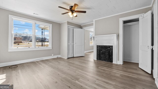 unfurnished bedroom with multiple closets, crown molding, hardwood / wood-style flooring, and ceiling fan