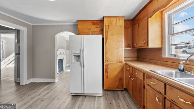 kitchen featuring ornamental molding, white refrigerator with ice dispenser, sink, and light hardwood / wood-style floors