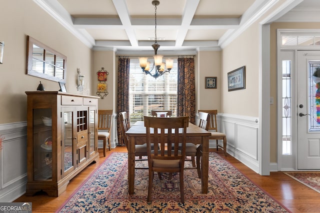 dining space featuring an inviting chandelier, coffered ceiling, beam ceiling, and hardwood / wood-style floors