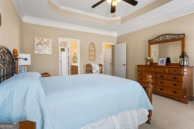 carpeted bedroom featuring ornamental molding, ensuite bath, ceiling fan, and a tray ceiling