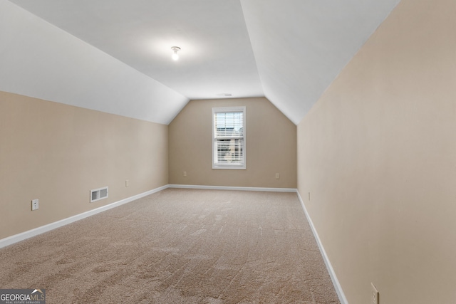 additional living space with light colored carpet and vaulted ceiling