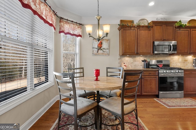 kitchen with pendant lighting, backsplash, crown molding, and stainless steel appliances