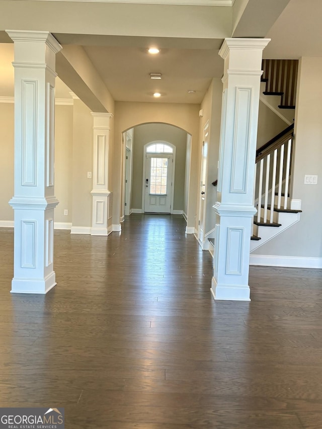 entryway featuring dark wood-type flooring and ornate columns