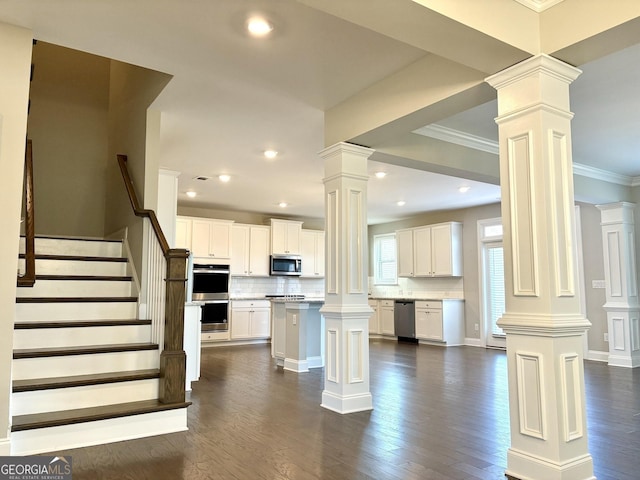 kitchen featuring white cabinetry, stainless steel appliances, a center island, and ornate columns