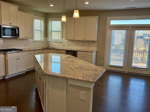 kitchen featuring a kitchen island, decorative light fixtures, white cabinetry, sink, and stainless steel appliances