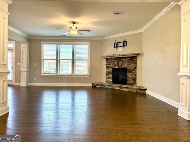 unfurnished living room featuring ornate columns, ornamental molding, a stone fireplace, and dark hardwood / wood-style floors