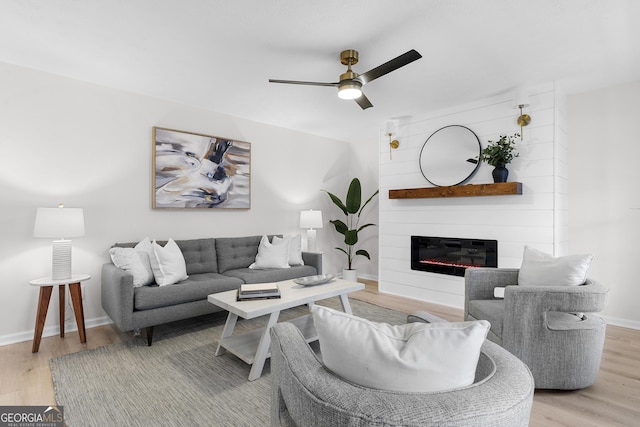 living room featuring ceiling fan, light wood-type flooring, and a fireplace