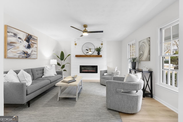 living room featuring a large fireplace, ceiling fan, and light hardwood / wood-style flooring