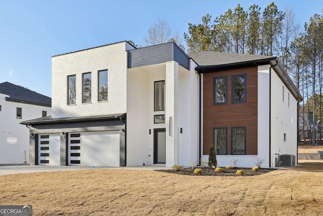 modern home with a garage, central AC unit, and a front yard