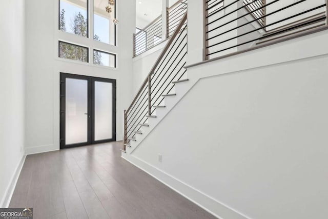 foyer featuring hardwood / wood-style flooring, a towering ceiling, and french doors