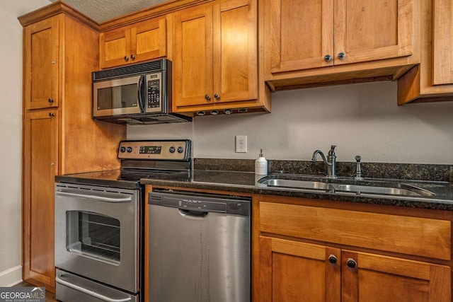 kitchen featuring stainless steel appliances, sink, and dark stone counters