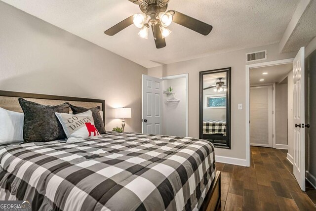 bedroom with dark hardwood / wood-style flooring, a textured ceiling, and ceiling fan