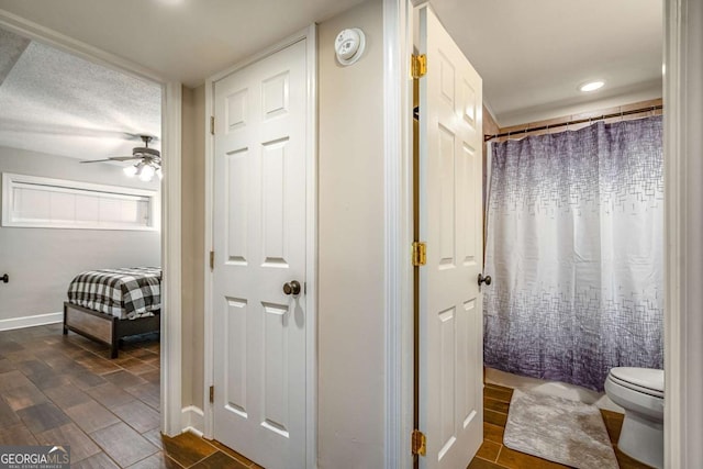 bathroom featuring a shower with curtain, ceiling fan, and toilet