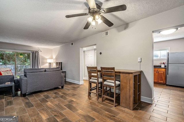 dining area featuring dark hardwood / wood-style flooring, ceiling fan, and a textured ceiling