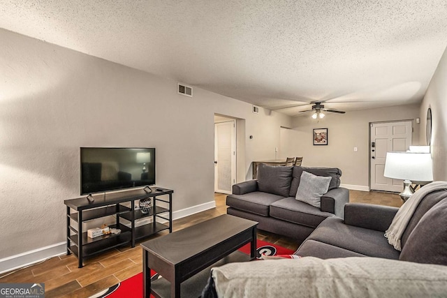 living room featuring ceiling fan and a textured ceiling