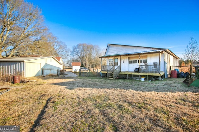 back of house featuring an outbuilding, a deck, and a lawn