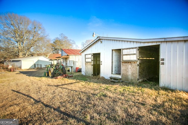 back of house with an outdoor structure and a lawn