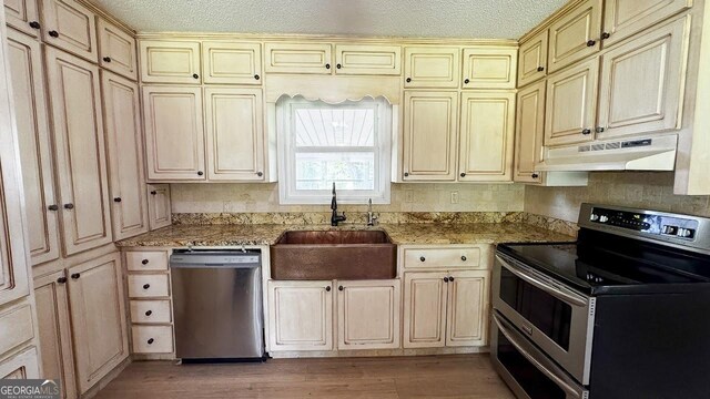 444 Agape Rd, Carrollton, GA 30116 - kitchen featuring appliances with stainless steel finishes, under cabinet range hood, cream cabinetry, a sink, and a textured ceiling