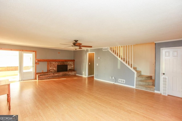 unfurnished living room with crown molding, ceiling fan, hardwood / wood-style floors, a fireplace, and a textured ceiling