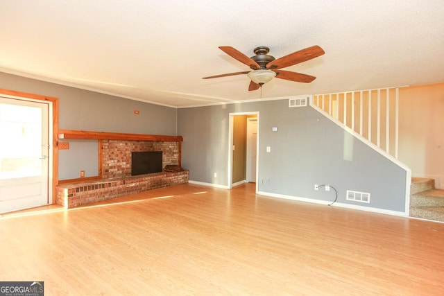 unfurnished living room featuring ceiling fan, ornamental molding, a fireplace, and hardwood / wood-style floors