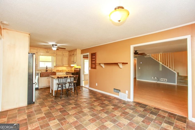 kitchen featuring sink, a breakfast bar area, crown molding, a center island, and stainless steel refrigerator