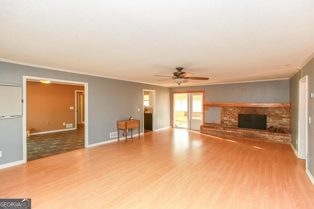 444 Agape Rd, Carrollton, GA 30116 - unfurnished living room with wood finished floors, ornamental molding, a brick fireplace, a ceiling fan, and baseboards