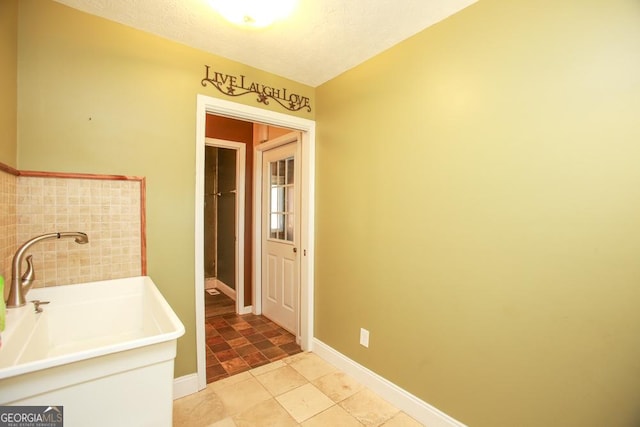 bathroom with a washtub, sink, and a textured ceiling