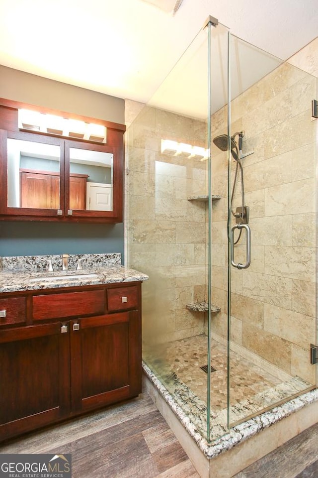 bathroom featuring wood-type flooring, a shower with door, and vanity