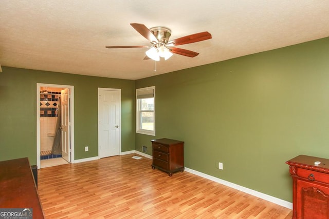 bedroom with ceiling fan, ensuite bathroom, light hardwood / wood-style floors, and a textured ceiling