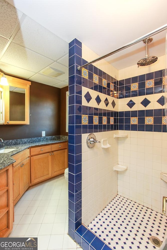 bathroom with tile patterned floors, vanity, and a tile shower