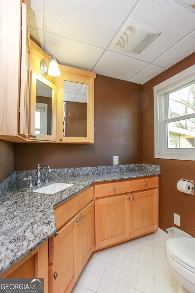 bathroom with vanity, tile patterned floors, toilet, and a drop ceiling