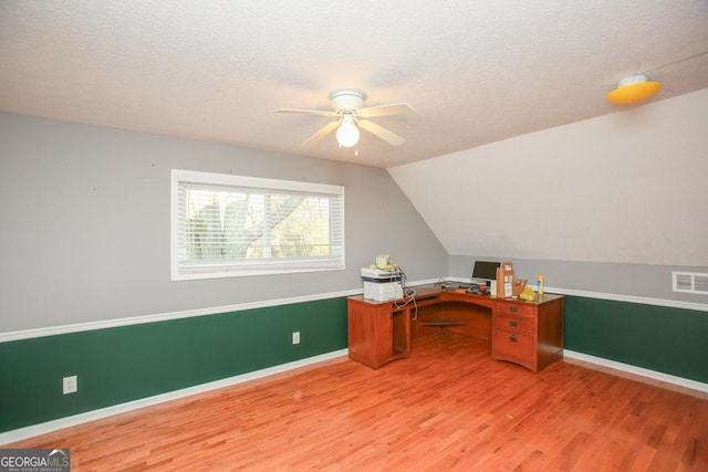 unfurnished office with wood-type flooring, vaulted ceiling, and a textured ceiling