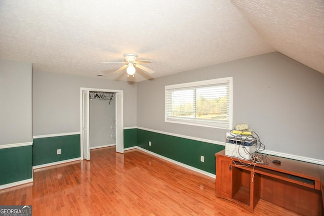 interior space with lofted ceiling, ceiling fan, a textured ceiling, and light wood-type flooring