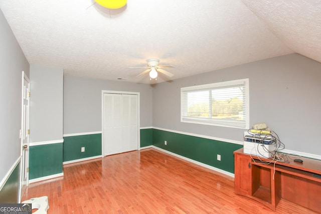 interior space featuring ceiling fan, vaulted ceiling, hardwood / wood-style floors, and a textured ceiling