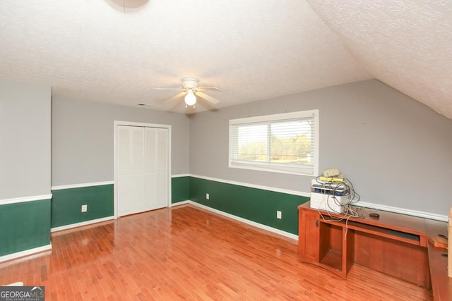 additional living space with hardwood / wood-style flooring, ceiling fan, vaulted ceiling, and a textured ceiling