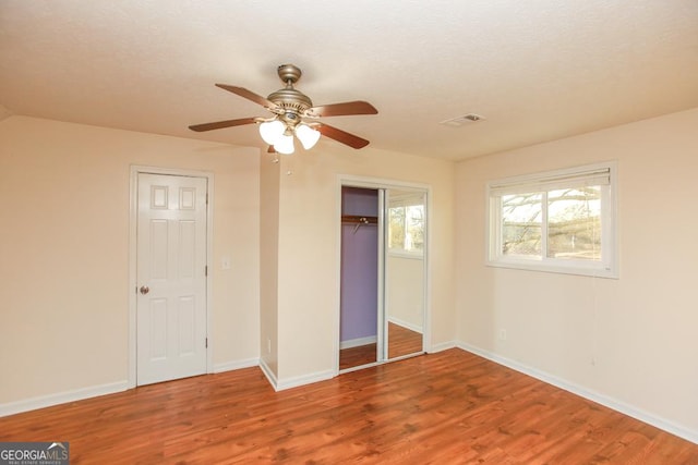 unfurnished bedroom with ceiling fan, wood-type flooring, a closet, and a textured ceiling