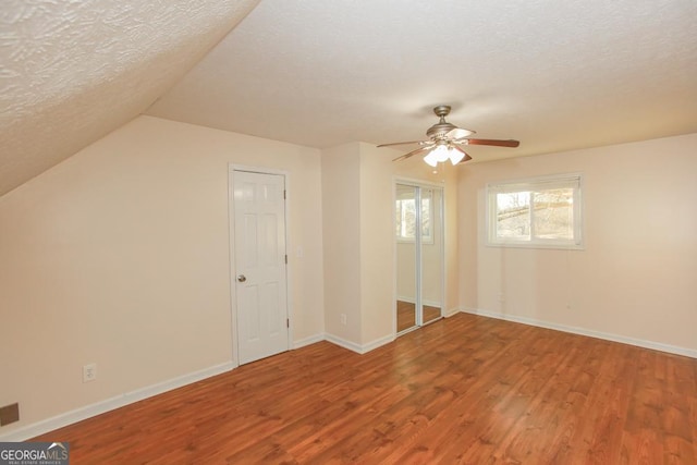 bonus room with ceiling fan, lofted ceiling, wood-type flooring, and a textured ceiling