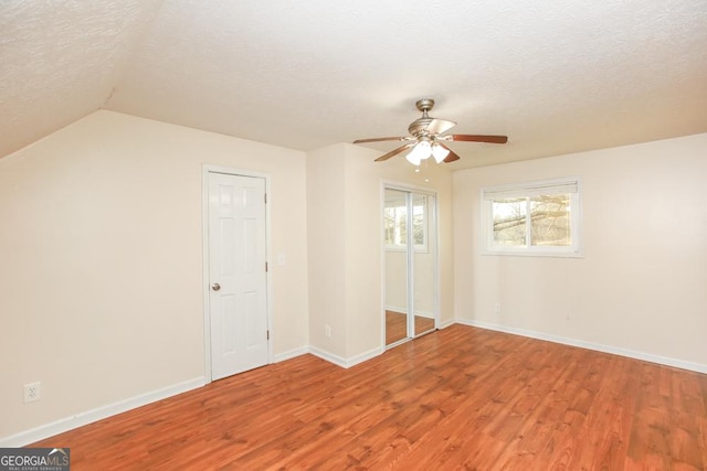 interior space with hardwood / wood-style flooring, ceiling fan, lofted ceiling, and a textured ceiling