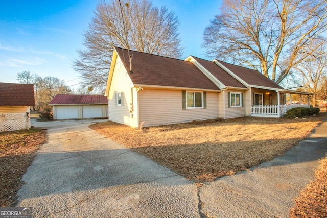 view of side of property with a garage, an outbuilding, and covered porch